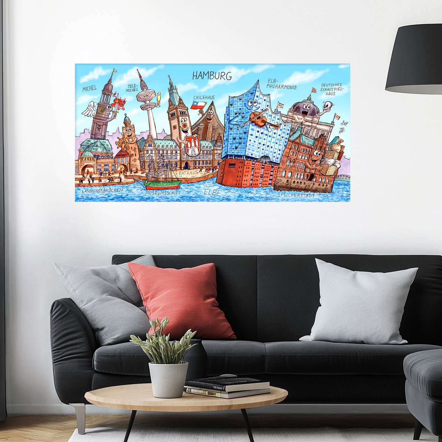 Jacques Tilly Hamburg Stadtbild als Acrylbild mit Alu-Rückrahmen über einem schwarzen Sofa mit einem roten und zwei grauen Kissen und einem runden Couchtisch aus Holz davor.