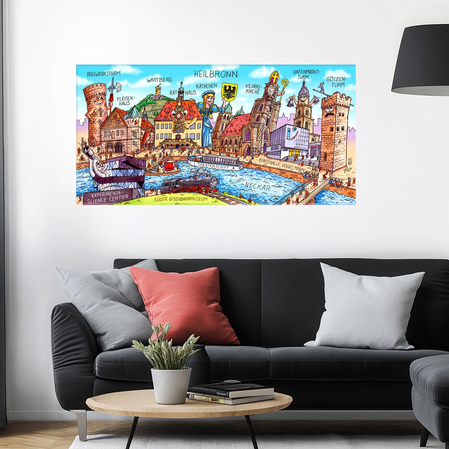 Jacques Tilly Heilbronn Stadtbild auf Leinwand mit Holzrahmen über einem schwarzen Sofa mit einem roten und zwei grauen Kissen und einem runden Couchtisch aus Holz davor.
