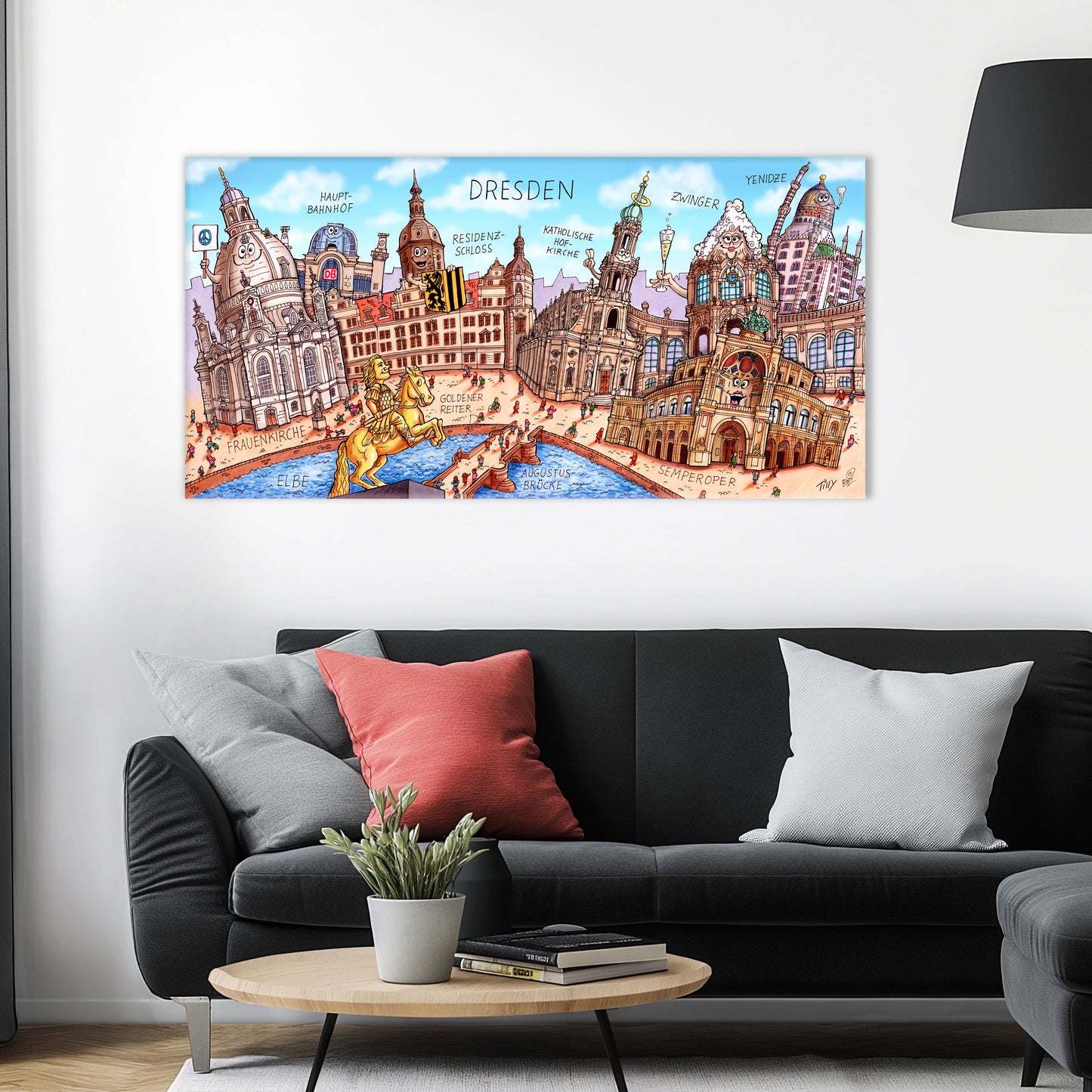 Jacques Tilly Dresden Stadtbild als Acrylbild mit Alu-Rückrahmen über einem schwarzen Sofa mit einem roten und zwei grauen Kissen und einem runden Couchtisch aus Holz davor.