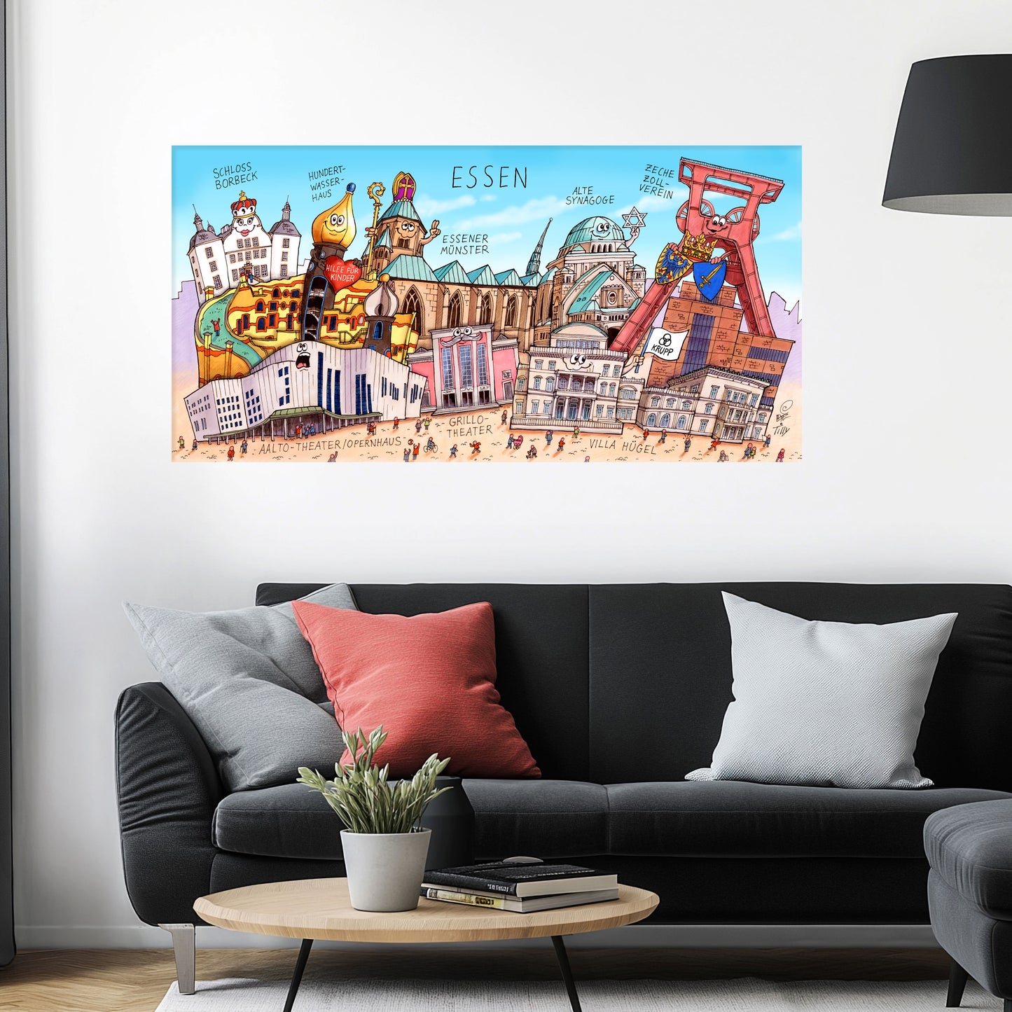 Jacques Tilly Essen Stadtbild auf Leinwand mit Holzrahmen über einem schwarzen Sofa mit einem roten und zwei grauen Kissen und einem runden Couchtisch aus Holz davor.