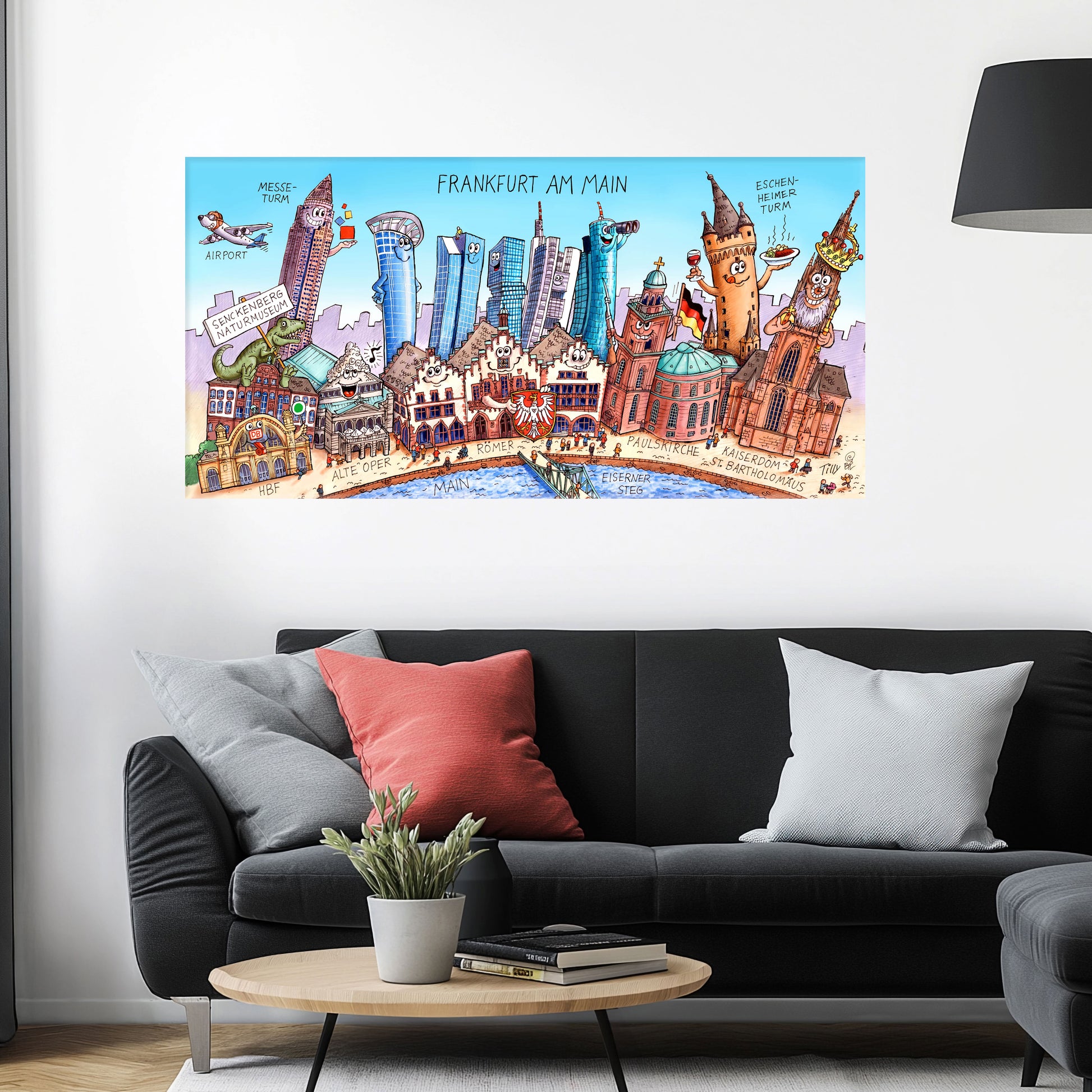 Jacques Tilly Frankfurt am Main Stadtbild als Acrylbild mit Alu-Rückrahmen über einem schwarzen Sofa mit einem roten und zwei grauen Kissen und einem runden Couchtisch aus Holz davor.
