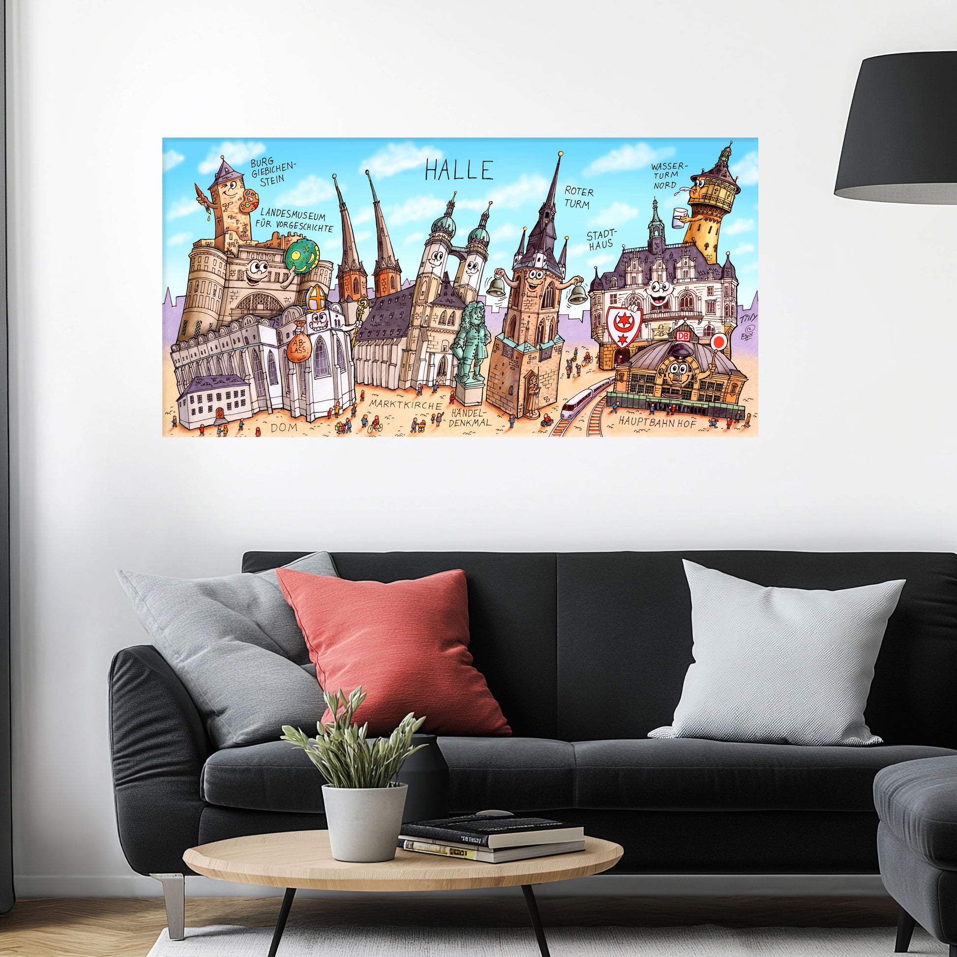 Jacques Tilly Halle an der Saale Stadtbild als Acrylbild mit Alu-Rückrahmen über einem schwarzen Sofa mit einem roten und zwei grauen Kissen und einem runden Couchtisch aus Holz davor.
