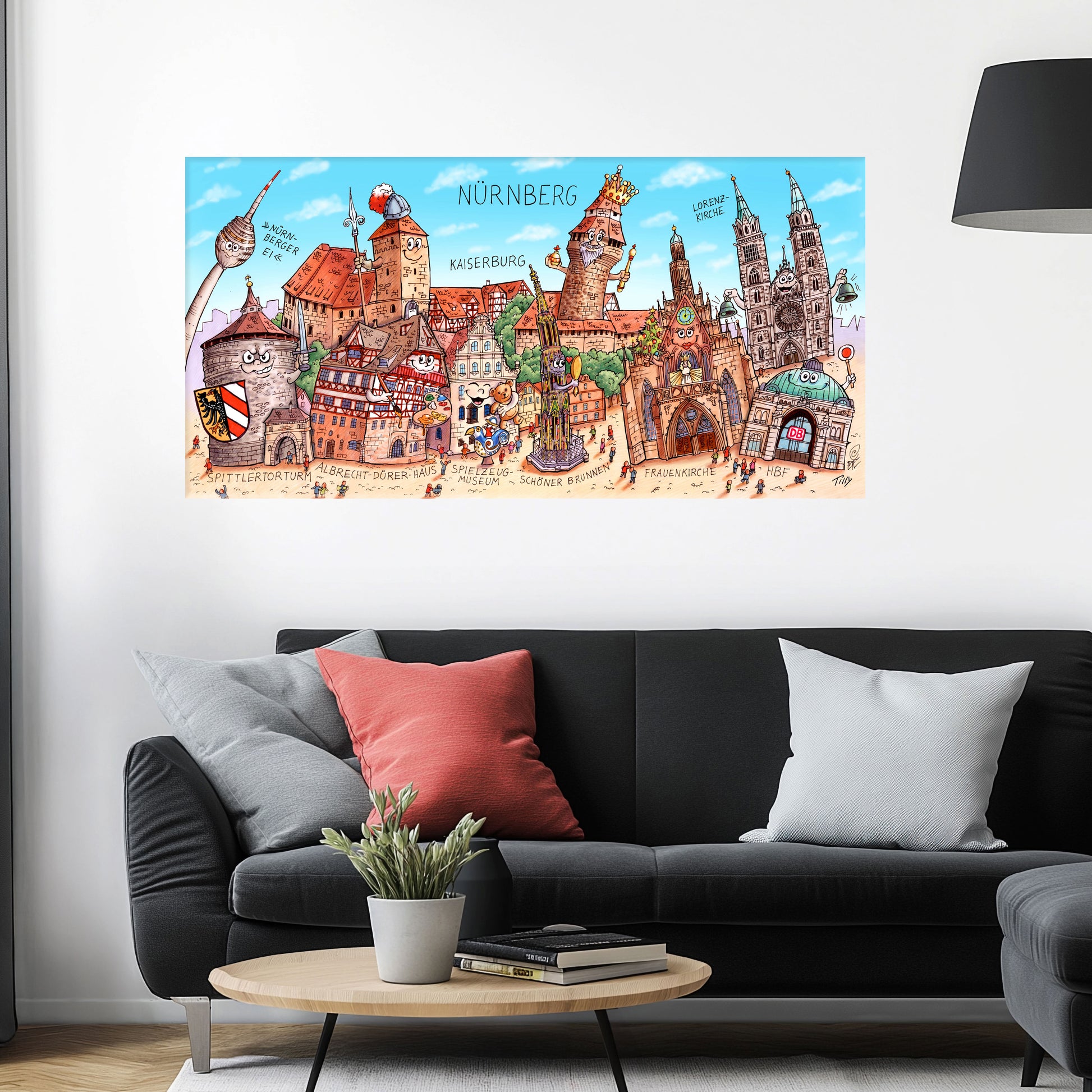 Jacques Tilly Nürnberg Stadtbild auf Leinwand mit Holzrahmen über einem schwarzen Sofa mit einem roten und zwei grauen Kissen und einem runden Couchtisch aus Holz davor.