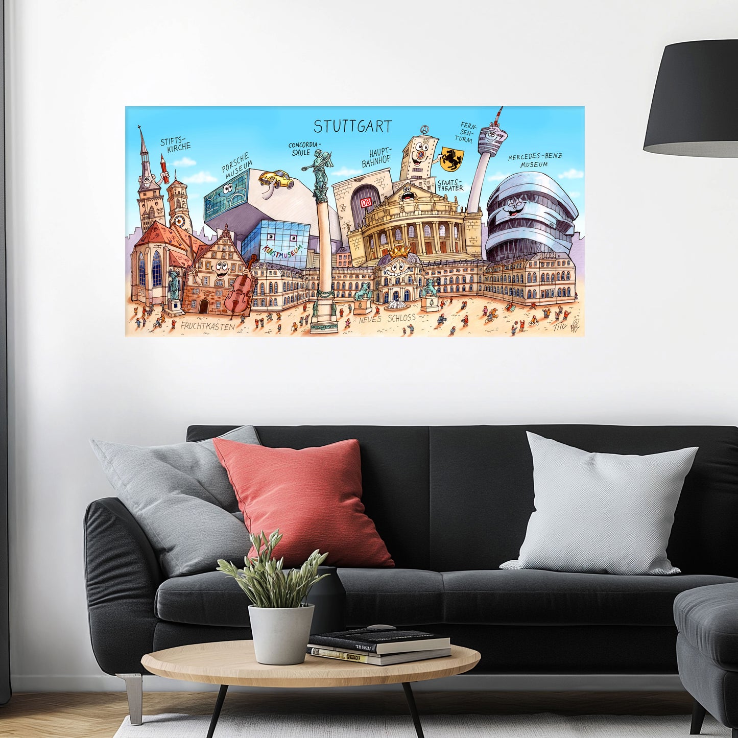 Jacques Tilly Stuttgart Stadtbild als Acrylbild mit Alu-Rückrahmen über einem schwarzen Sofa mit einem roten und zwei grauen Kissen und einem runden Couchtisch aus Holz davor.