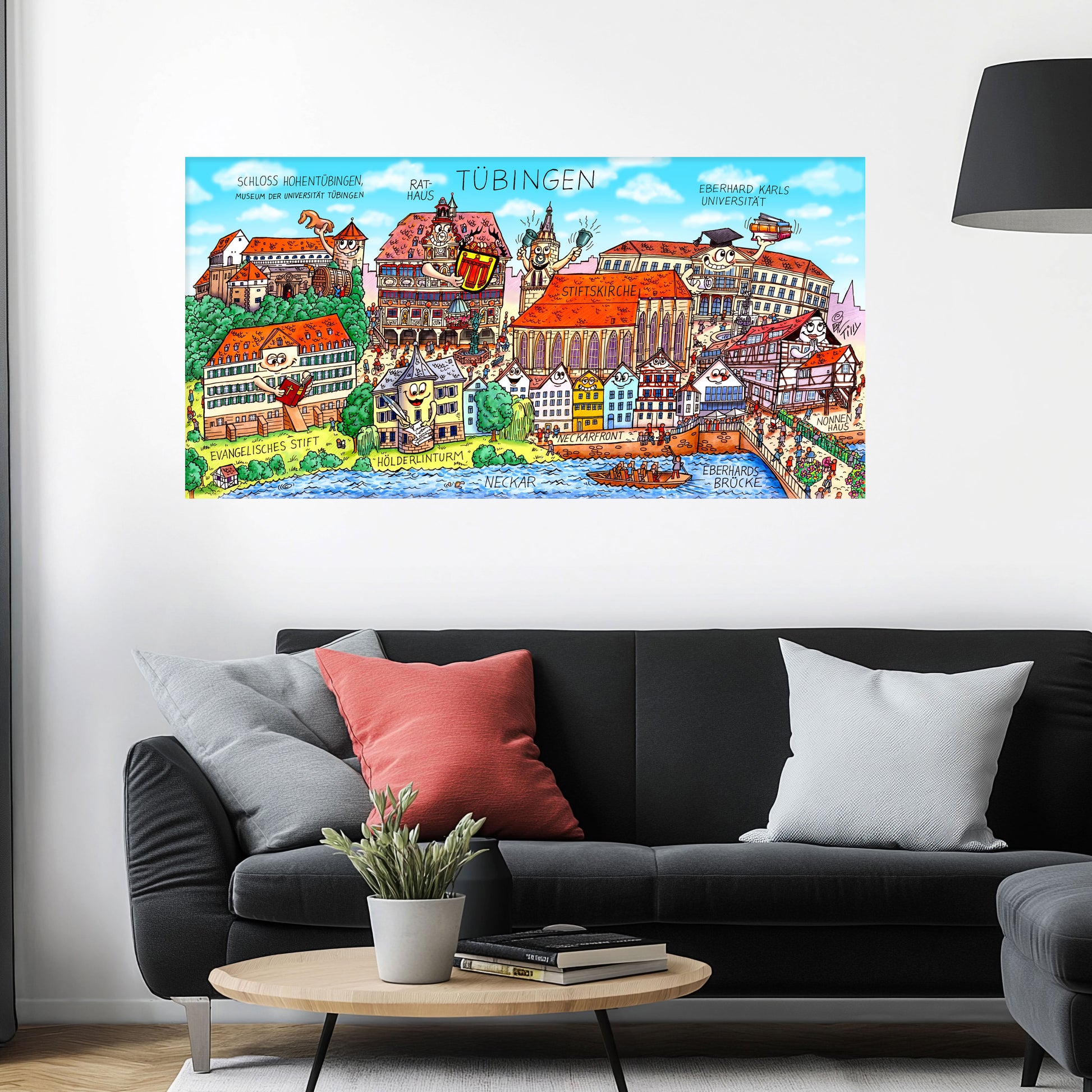 Jacques Tilly Tübingen Stadtbild auf Leinwand mit Holzrahmen über einem schwarzen Sofa mit einem roten und zwei grauen Kissen und einem runden Couchtisch aus Holz davor.